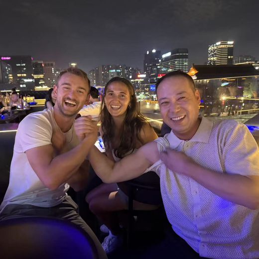 Alec arm wrestling a friend at a rooftop bar