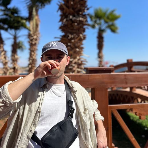 Alec sipping coffee under palm trees